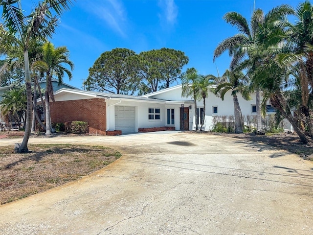 719 59th Ave, St Pete Beach, FL 33706 - view of front of property with a garage, brick siding, concrete driveway, and stucco siding