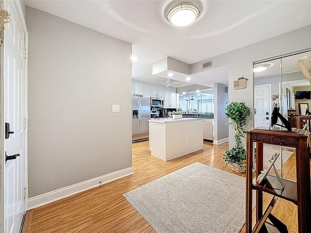 120 1st St E Unit 104, Saint Petersburg, FL 33715 - kitchen with stainless steel appliances, light wood-style flooring, white cabinets, and a kitchen island