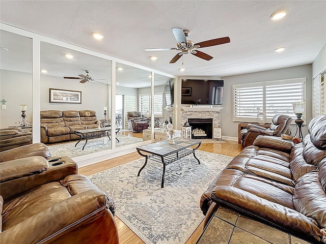 120 1st St E Unit 104, Saint Petersburg, FL 33715 - living room featuring a ceiling fan, a stone fireplace, a textured ceiling, light wood-type flooring, and recessed lighting