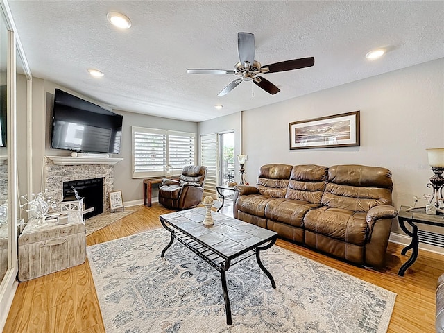 120 1st St E Unit 104, Saint Petersburg, FL 33715 - living room featuring a textured ceiling, a ceiling fan, wood finished floors, a stone fireplace, and recessed lighting