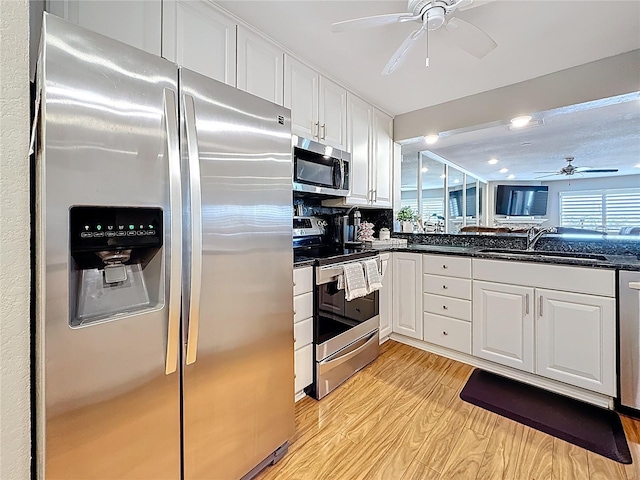 120 1st St E Unit 104, Saint Petersburg, FL 33715 - kitchen with stainless steel appliances, a ceiling fan, light wood finished floors, white cabinetry, and dark stone countertops