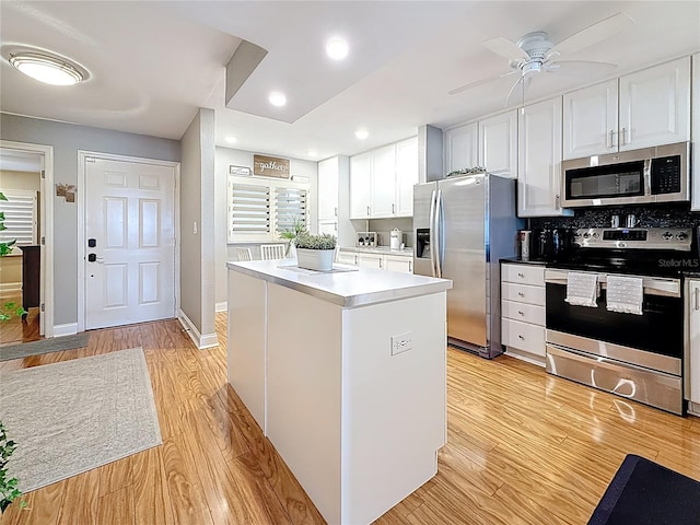 120 1st St E Unit 104, Saint Petersburg, FL 33715 - kitchen featuring stainless steel appliances, light wood-style flooring, a ceiling fan, white cabinetry, and a kitchen island