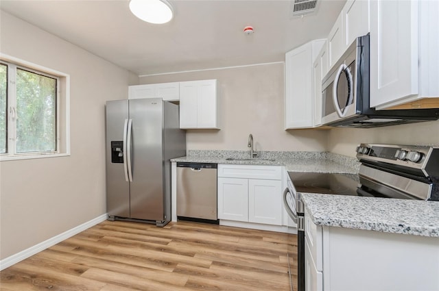 1727 Bonita Ave, Orlando, FL 32805 - kitchen featuring stainless steel appliances, a sink, light wood-type flooring, white cabinetry, and light stone counters