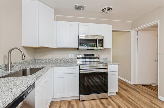 1727 Bonita Ave, Orlando, FL 32805 - kitchen featuring appliances with stainless steel finishes, a sink, light wood-style flooring, and white cabinetry