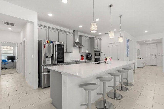 921 Fieldstone Way, Haines City, FL 33844 - kitchen featuring stainless steel appliances, wall chimney range hood, gray cabinetry, light countertops, and a center island with sink