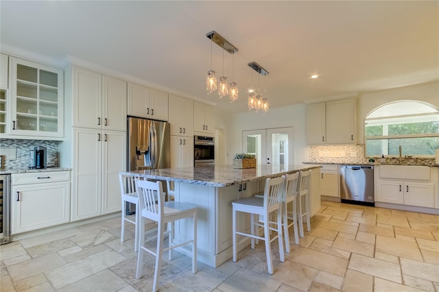 1089 Virginia St, Dunedin, FL 34698 - kitchen with stainless steel appliances, backsplash, light stone counters, stone tile flooring, and a kitchen island