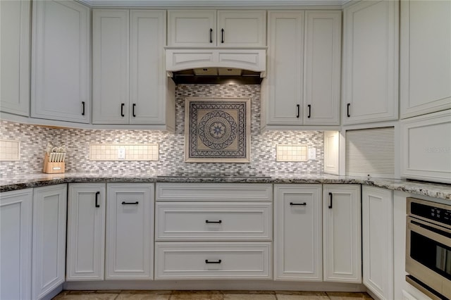 1089 Virginia St, Dunedin, FL 34698 - kitchen featuring stainless steel oven, backsplash, light stone countertops, and exhaust hood