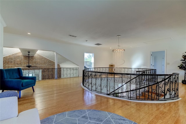 1089 Virginia St, Dunedin, FL 34698 - hallway with an upstairs landing, wood finished floors, a chandelier, brick wall, and ornamental molding