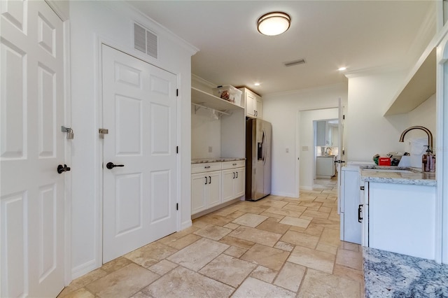 1089 Virginia St, Dunedin, FL 34698 - kitchen with stainless steel refrigerator with ice dispenser, ornamental molding, stone tile flooring, a sink, and white cabinets