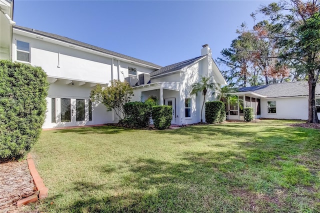 1089 Virginia St, Dunedin, FL 34698 - back of property with a chimney, a lawn, stucco siding, and french doors