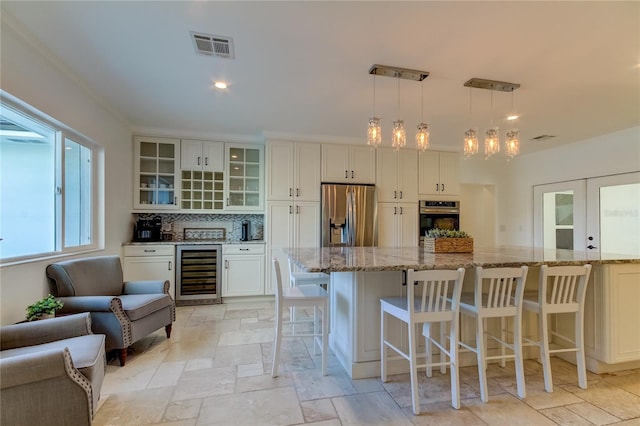 1089 Virginia St, Dunedin, FL 34698 - kitchen featuring appliances with stainless steel finishes, beverage cooler, stone tile flooring, light stone counters, and glass insert cabinets