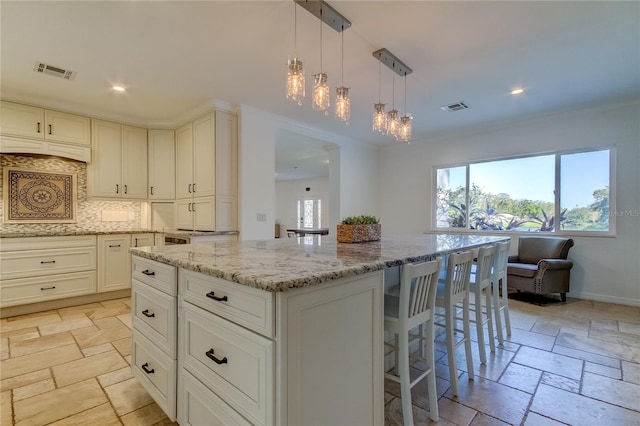 1089 Virginia St, Dunedin, FL 34698 - kitchen featuring stone tile flooring, light stone counters, tasteful backsplash, a center island, and recessed lighting