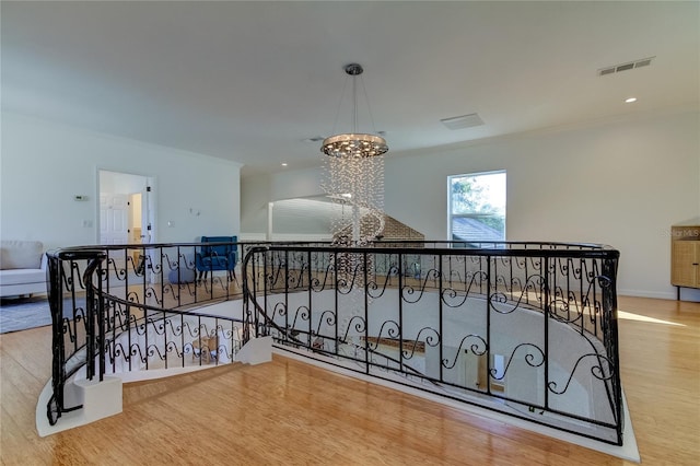 1089 Virginia St, Dunedin, FL 34698 - hall featuring crown molding, a chandelier, wood finished floors, an upstairs landing, and baseboards