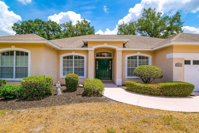 2214 Deerbrook Dr, Lakeland, FL 33811 - entrance to property featuring stucco siding, a garage, and roof with shingles