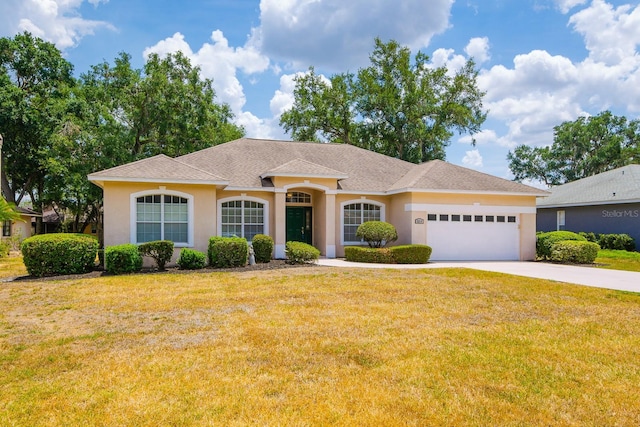 2214 Deerbrook Dr, Lakeland, FL 33811 - view of front of house featuring stucco siding, a garage, concrete driveway, a front lawn, and a shingled roof
