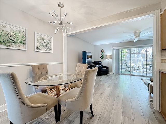 dining area with light wood-type flooring, a chandelier, and a ceiling fan