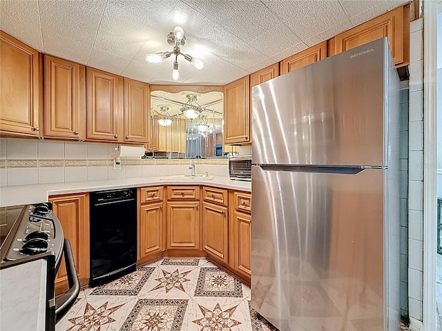 kitchen featuring freestanding refrigerator, a sink, black / electric stove, light countertops, and brown cabinets