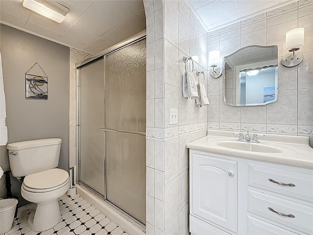 bathroom with a shower stall, toilet, tile walls, and vanity