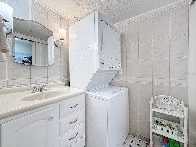 bathroom with estacked washer and dryer, tile walls, and vanity