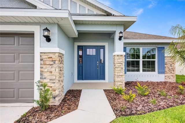 view of exterior entry featuring stone siding, stucco siding, a shingled roof, and an attached garage