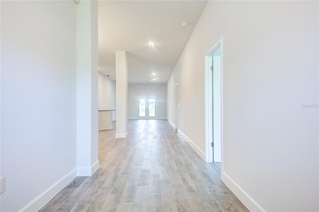 hallway with light wood-type flooring and baseboards