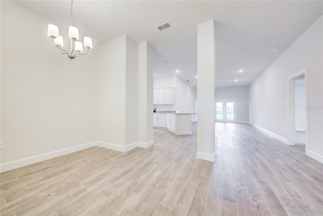unfurnished living room with light wood-style floors, baseboards, a chandelier, and recessed lighting
