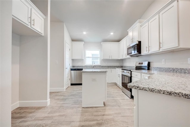 kitchen with stainless steel appliances, a center island, a sink, recessed lighting, and white cabinetry