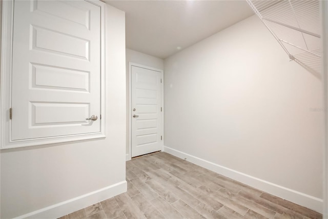 empty room featuring baseboards and light wood finished floors
