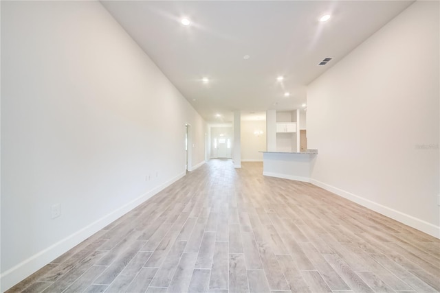 unfurnished living room with light wood-type flooring, baseboards, and recessed lighting