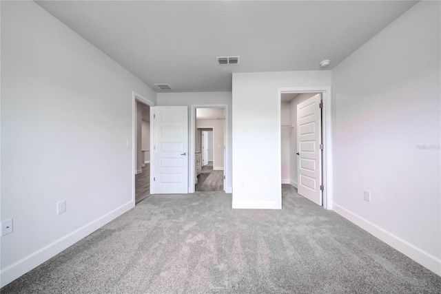 unfurnished bedroom featuring carpet, baseboards, and a walk in closet