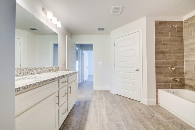full bath featuring wood finished floors, double vanity, baseboards, and shower / washtub combination