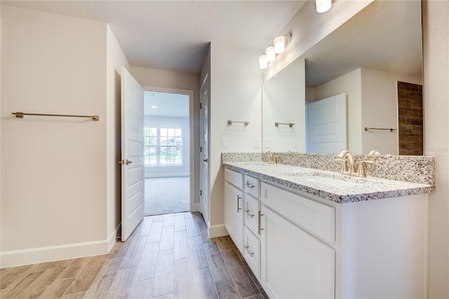 full bathroom featuring wood finished floors, double vanity, and baseboards
