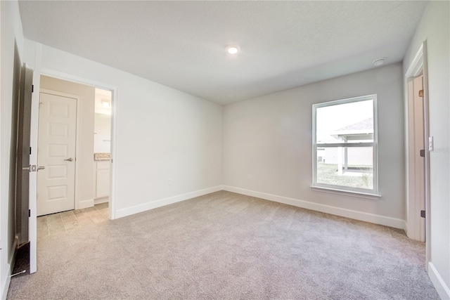 spare room with light colored carpet, baseboards, and recessed lighting