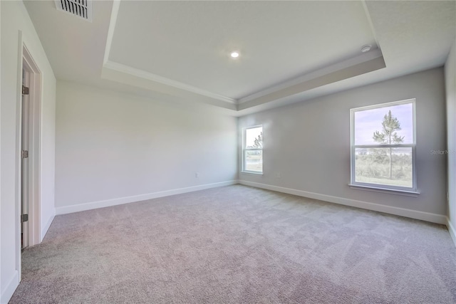 carpeted empty room with a tray ceiling, baseboards, ornamental molding, and recessed lighting