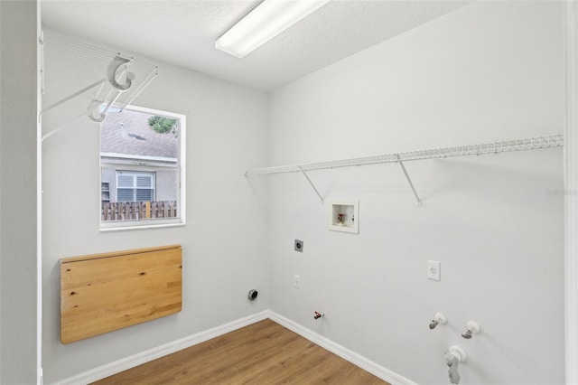 clothes washing area with gas dryer hookup, hookup for a washing machine, wood finished floors, electric dryer hookup, and baseboards