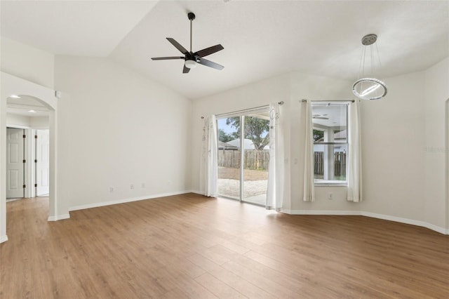 unfurnished living room featuring a ceiling fan, arched walkways, light wood-style flooring, baseboards, and lofted ceiling