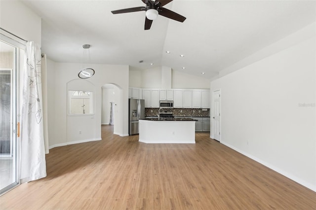 unfurnished living room featuring ceiling fan, arched walkways, light wood-style floors, a sink, and recessed lighting