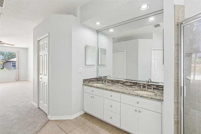 full bathroom with recessed lighting, double vanity, a tile shower, tile patterned floors, and baseboards