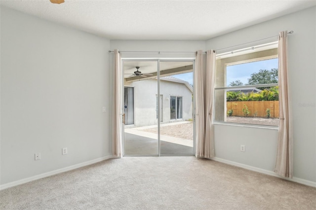 carpeted empty room with a ceiling fan and baseboards
