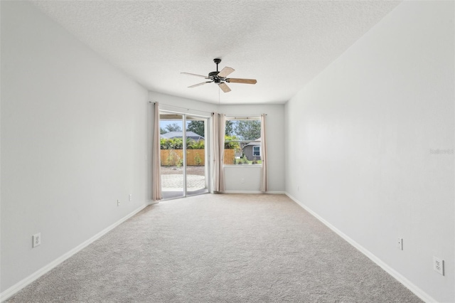 spare room with ceiling fan, light colored carpet, a textured ceiling, and baseboards