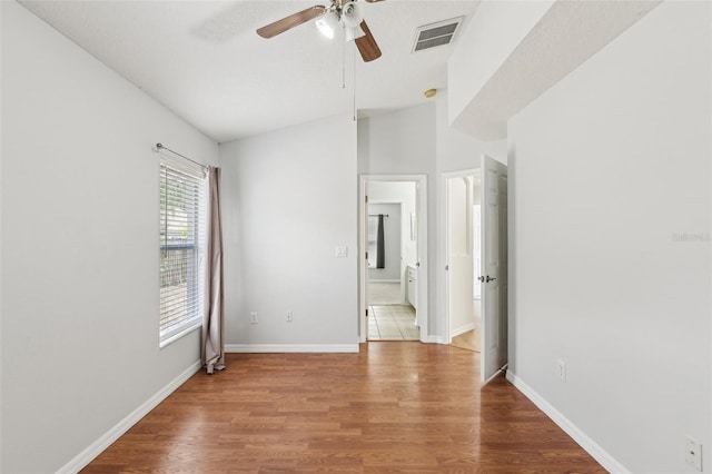 unfurnished bedroom with wood finished floors, ensuite bathroom, and baseboards