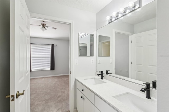 bathroom with a ceiling fan, double vanity, and a textured ceiling