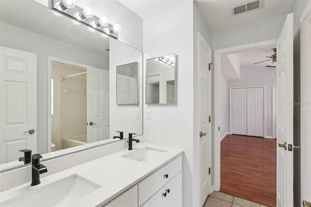 full bathroom featuring toilet, tile patterned floors, double vanity, and shower / bathtub combination