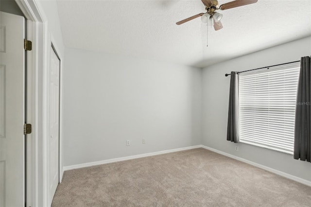 unfurnished bedroom featuring light carpet, baseboards, a ceiling fan, and a closet