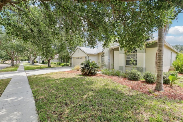 view of front of house featuring stucco siding, driveway, a garage, and a front lawn