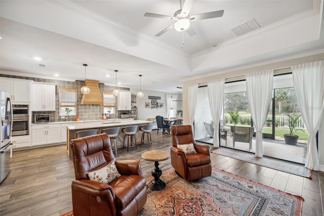 22294 Storybook Cabin Way, Land O Lakes, FL 34637 - living room with wood finished floors, crown molding, a ceiling fan, a raised ceiling, and recessed lighting