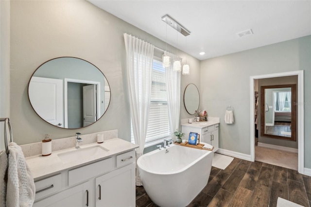 22294 Storybook Cabin Way, Land O Lakes, FL 34637 - full bath featuring wood finish floors, a freestanding bath, two vanities, and baseboards