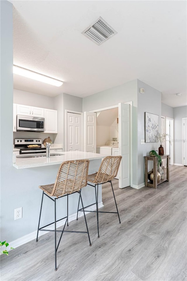 dining room with independent washer and dryer, light wood-style flooring, and baseboards