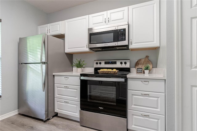kitchen with stainless steel appliances, light countertops, light wood-style flooring, and white cabinetry