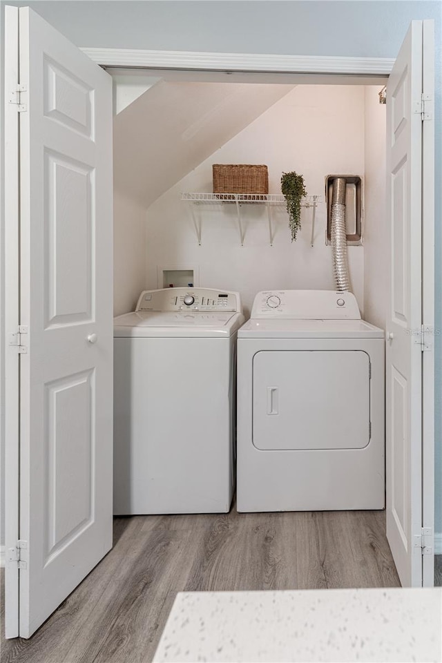 laundry room with washing machine and clothes dryer and light wood-style floors